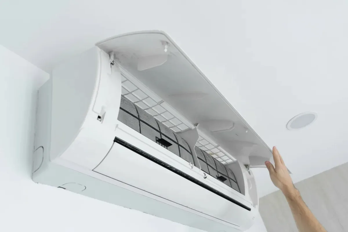 Hand opening the cover of a wall-mounted ductless air conditioner